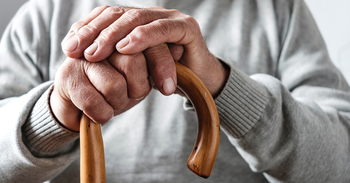 Close-up of an elderly person's hands holding a wooden cane, symbolizing support and guidance in elder law services.