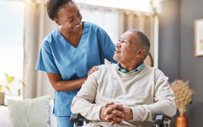 An Elder Care Nurse With A Male Patient Who Is In A Wheelchair In A Long-term Care Facility In Kentucky.