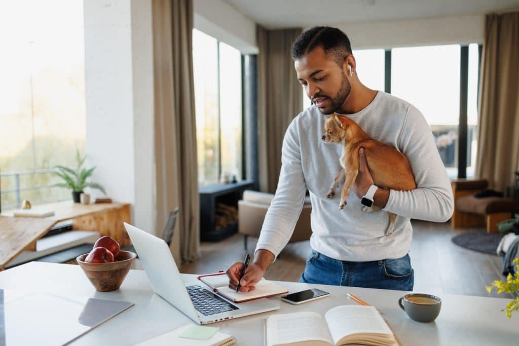 A single man holding a small dog makes an estate plan for his property and the care of his pet. 