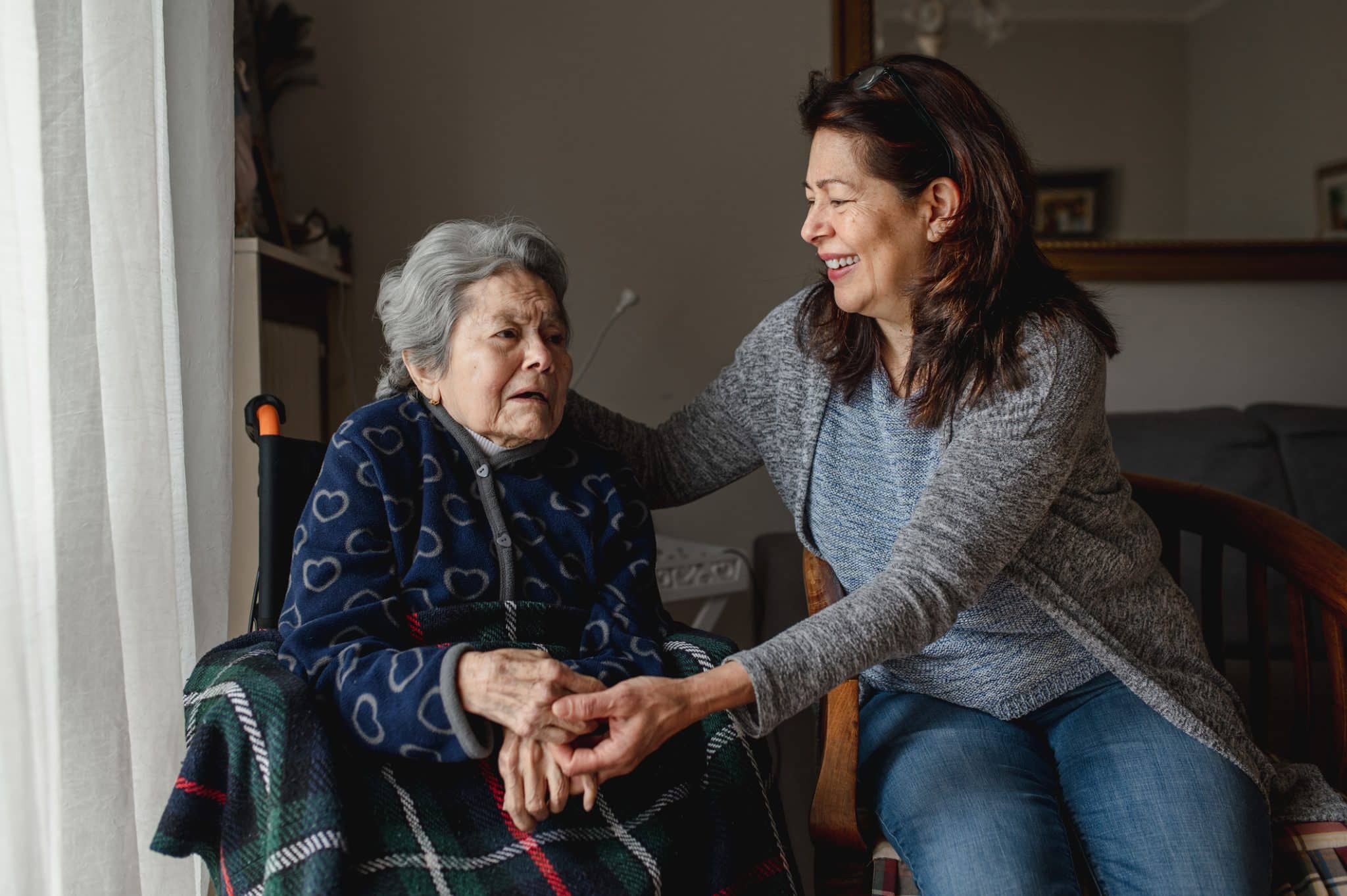 A woman sits with her elderly mother as she considers becoming a family caregiver.