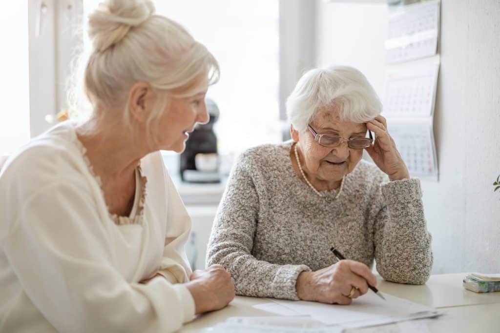 A woman sits with her elderly mother, going over legal documents.