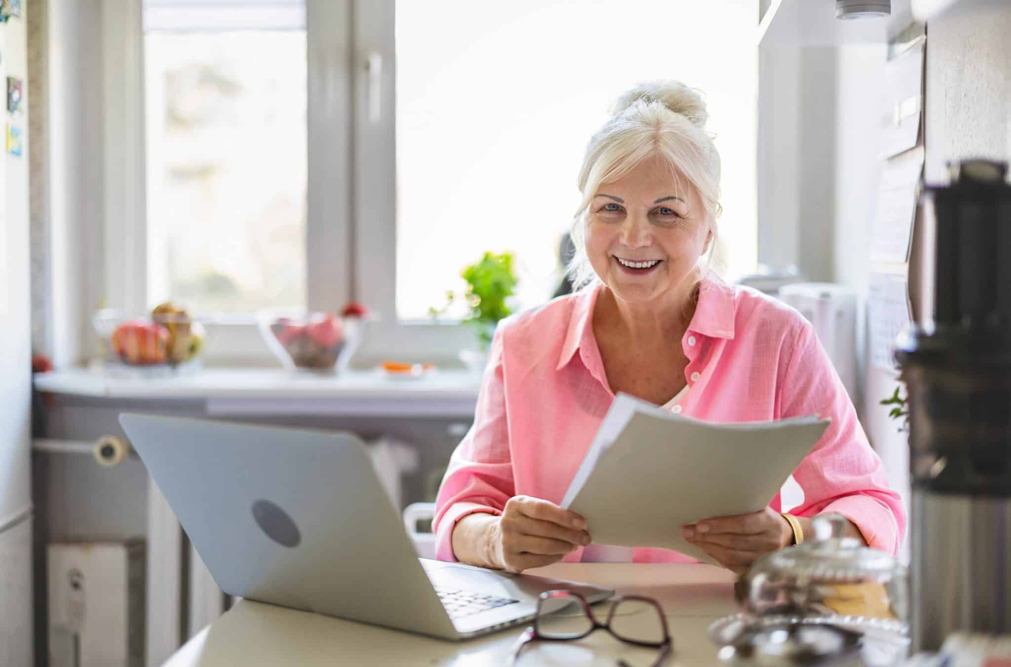 A woman sits with her computer and some estate planning documents, working on her New Year’s resolutions.