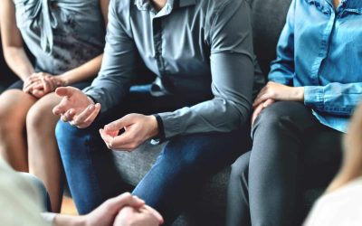 A partial view of people sitting in a group on sofas, representing a family managing a dispute or discussing estate planning.