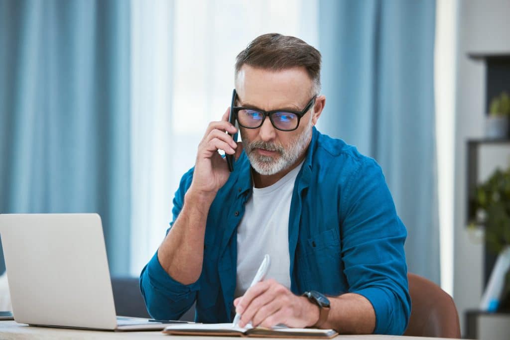 A man on the phone with an elder law attorney looks at paperwork to determine medicaid eligibility for nursing home care.