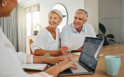 An older couple sits at a table with an attorney reviewing documents about asset protection and estate planning.
