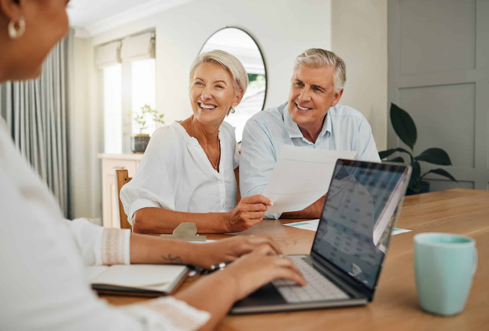 An older couple sits at a table with an attorney reviewing documents about asset protection and estate planning.