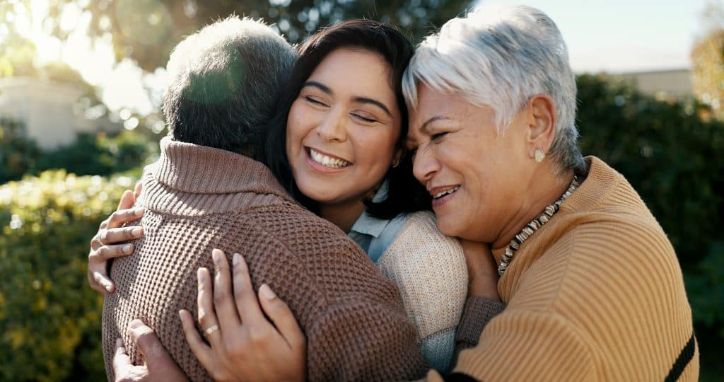 A Kentucky woman hugs her elderly parents after navigating retirement planning together.